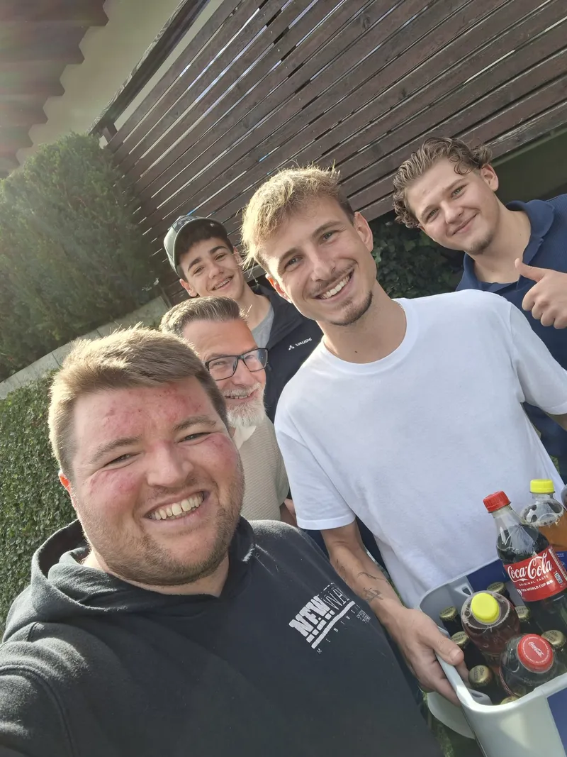 Flo übergibt vier Kunden im Garten eine Kiste mit Cola und Bier